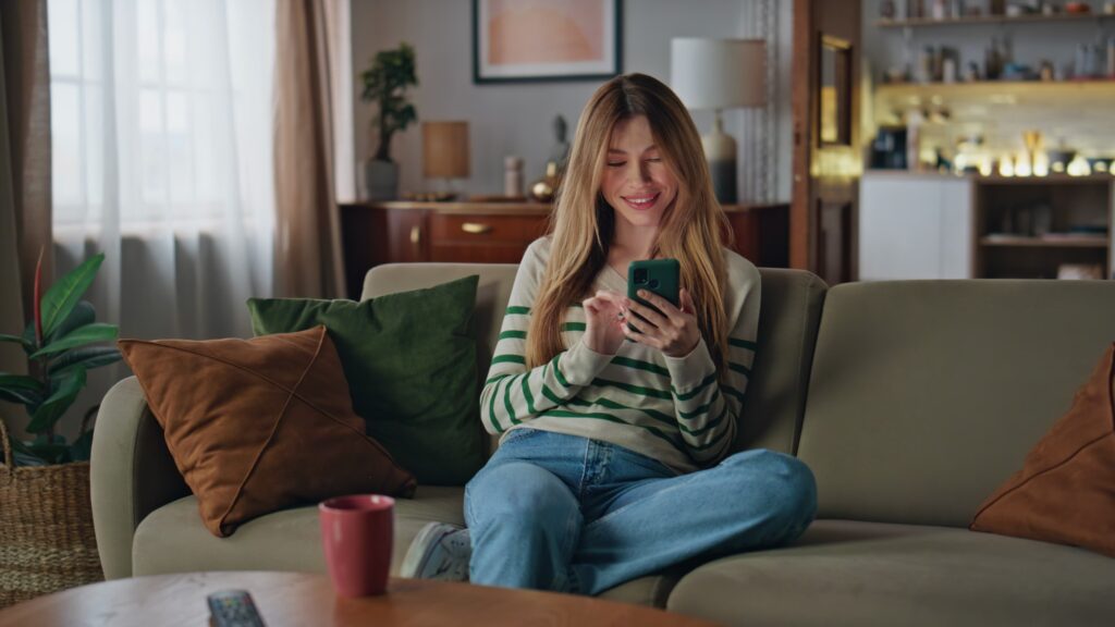 Woman ordering cannabis delivery from home on couch in MA